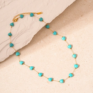 Vue détaillée du collier doré avec perles en forme de cœur turquoise et fermoir mousqueton