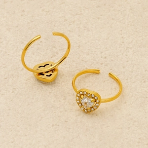Detailed macro view of gold heart-shaped zircon rings on a textured fabric surface