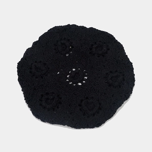 Close-up of black hollow crochet beret showing detailed floral knit texture and cotton yarn