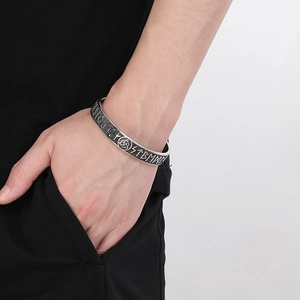 Close-up of vintage Viking Odin rune engraved stainless steel cuff bracelet on male wrist