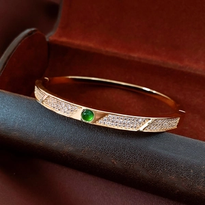 Macro detail of 18K gold plated bracelet with micro-pave zircons and green gemstone