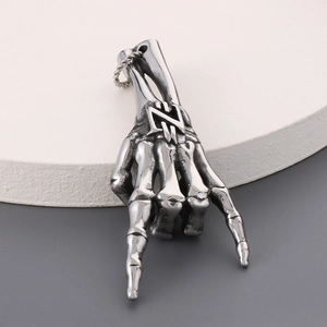 Macro shot of silver stainless steel skeleton hand rock gesture pendant with runes