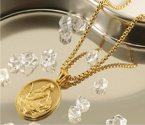 Macro view of gold stainless steel religious pendant with textured box chain details