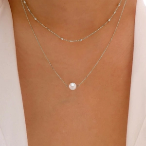 Detail of layered silver chain with a round white freshwater pearl pendant on a model