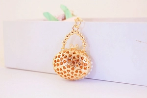 Detail view of a golden hollow heart pattern handbag charm on a white gift box