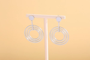 Close-up of silver geometric triple concentric circle drop earrings on display
