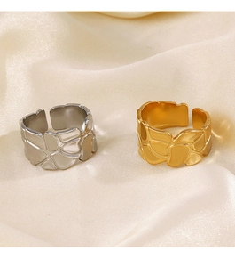 Detailsicht goldener und silberner Ringe mit Lava-Textur auf beige Satin-Stoff