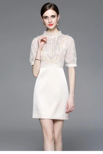 Detail of white dress featuring intricate lace, heavy beadwork, and puff sleeves