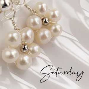 Macro detail of handmade freshwater pearl flower cluster earrings with silver wire weaving