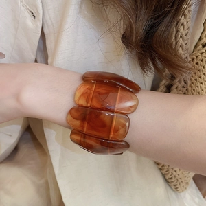 Detail view of the amber resin marbled wide bracelet showing retro pattern and texture