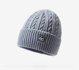 Detail view of light grey cable knit beanie showing thick texture and woven label