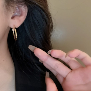 Close-up of minimalist gold metal hoop earrings worn by a model for a chic look