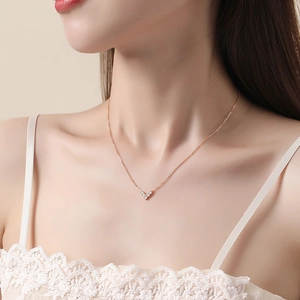 Elegant V-shaped rose gold necklace with zircon stones worn by a model on a beige background