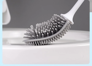 Detailed view of grey flat TPR toilet brush head cleaning under the white toilet rim
