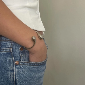 Bracciale rigido aperto in acciaio argento con doppia goccia lucida indossato dal modello