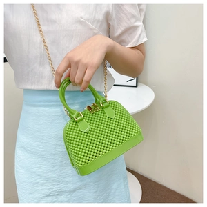 Detail of green jelly shell bag with pearl texture and a gold chain strap for women