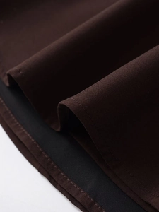 Détail de la texture du tissu marron foncé avec coutures fines et doublure noire de robe