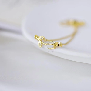 Detail of gold tulip bracelet featuring white cat-eye stone and crystal leaf charm
