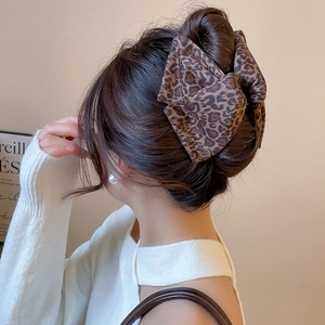 Detail of a leopard print fabric bow hair claw clip worn on a bun for elegant hairstyling