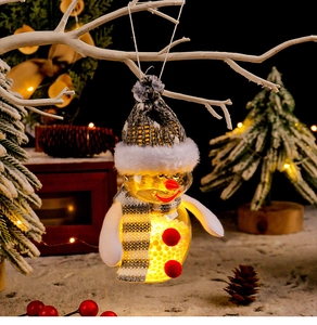 Detail of a glowing Christmas snowman ornament with LED lights hanging on a snowy branch