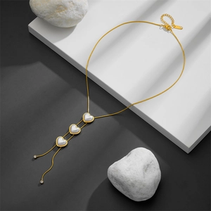 Elegant gold heart pendant necklace with three pearl-like stones on a sleek chain