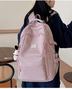 Rear view of a pink multi-pocket nylon backpack featuring side buckles and adjustable straps