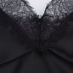 Dettaglio del bordo in pizzo e del tessuto satinato su un top nero con scollo a V