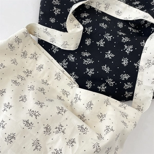 Detail of floral canvas crossbody bags showing black and beige patterns with a shoulder strap