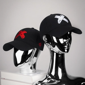 Black casual baseball caps with red and white X embroidery on metallic mannequin heads