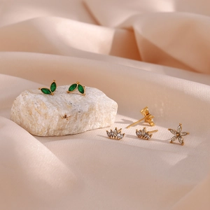 Detailed view of gold stainless steel zircon floral stud earrings on pink satin