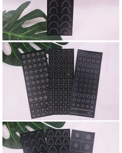 Detail of heart and butterfly nail art stencils with black templates on green leaf