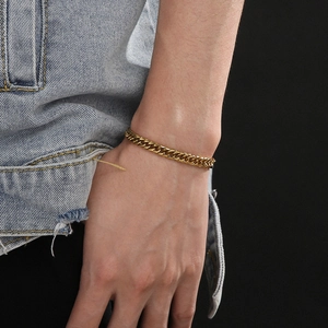Gros plan détaillé d'un bracelet gourmette en or 18 carats porté avec une veste en jean