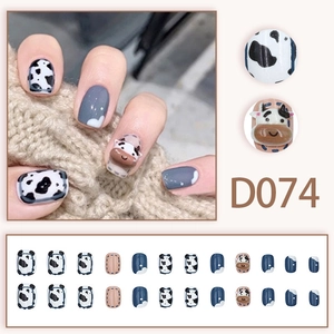 Press-on nails featuring cow print patterns and 3D cartoon cows in blue and white