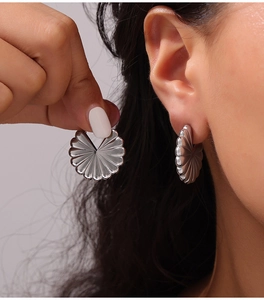 Close-up of pleated fan-shaped silver drop earrings with high-polish metallic finish