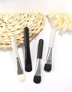 Close-up of four flat facial mask brushes with soft synthetic bristles and smooth handles