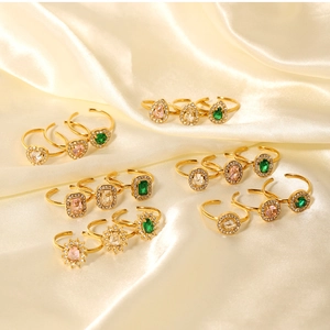 Close-up of vintage gold rings with emerald and pink zircon on champagne satin background