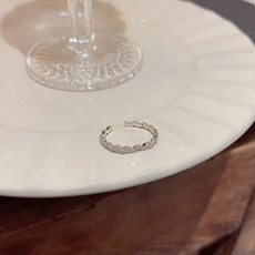 Detail shot of a silver butterfly ring with wavy scallop pattern on a ceramic dish