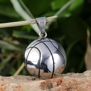 Polished basketball pendant made of stainless steel displayed on a natural rock