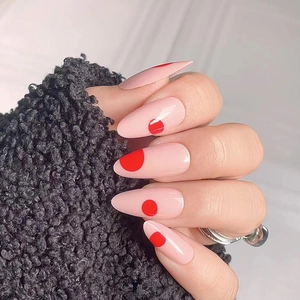 Minimalist almond press-on nails with soft nude base and bold red polka dot design