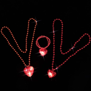 Close-up of three red beaded necklaces with glowing LED heart pendants on black.
