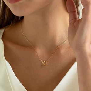 Close-up of 18k gold heart pendant necklace on neck showing hollow design and delicate chain