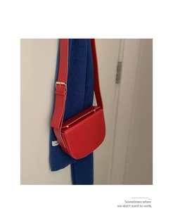 Red PU leather saddle bag detail with wide strap against navy blue scarf background