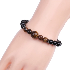 Black onyx and tiger eye 8mm beaded bracelet worn on wrist over a white background