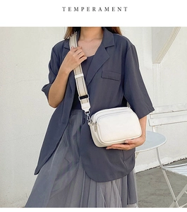 Modern white crossbody bag with striped wide strap worn by model against minimalist background
