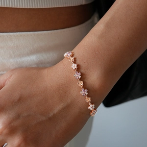 Detail of rose gold flower bracelet with pearls and purple zircons on model wrist