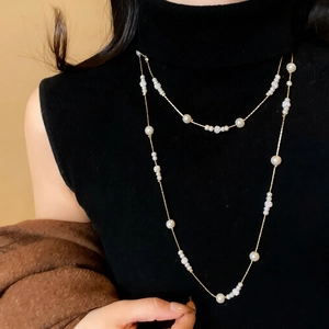 Close-up of double-layer long pearl necklace with diamond accents on black sweater