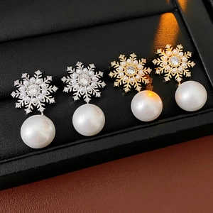 Vue macro de boucles d'oreilles perles flocon de neige vintage en doré et argenté