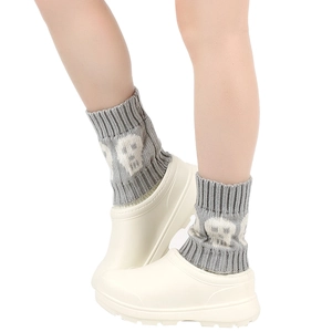 Detail showing grey knitted leg warmers with white skull patterns and casual shoes