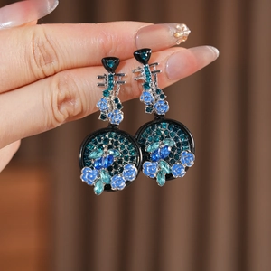 Dettaglio macro di orecchini vintage a fiore e liuto con strass blu e perni in argento