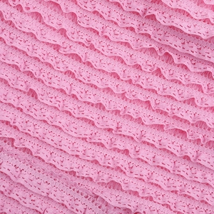 Vue détaillée du tissu en dentelle rose texturée avec d'élégants volants superposés